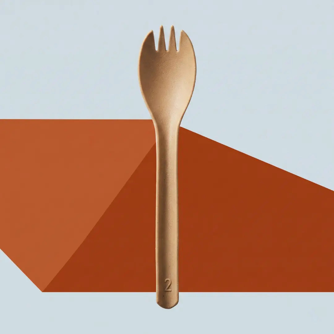 CompostEase | Spork standing vertically against a minimalist background with bold orange accent, showcasing modern compostable cutlery design.