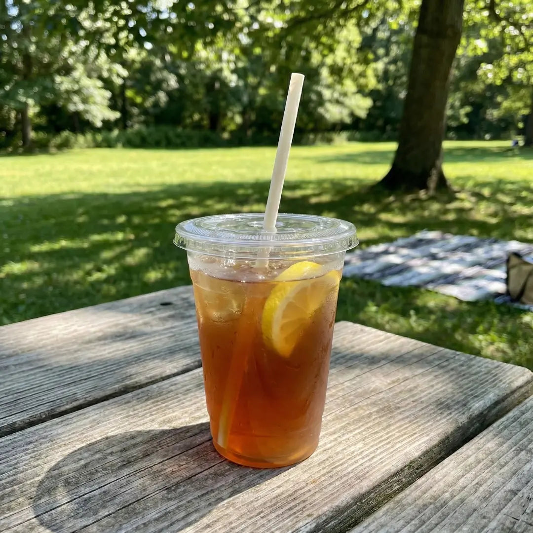 CompostEase 6mm compostable straw in iced tea with lemon, placed on a picnic table in a sunny outdoor setting.